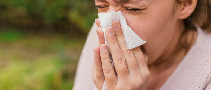 Seasonal virus infection. Sick young woman with seasonal influenza blowing her nose on a tissue. Woman has sneezing.  This flu is getting to her. Young woman coughing covering her mouth with a tissue